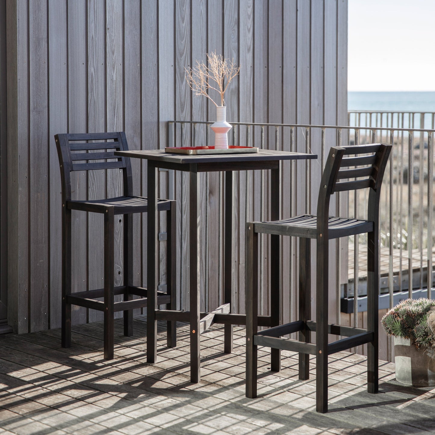 Two Alfrington 2 Seater High Bar Set Black chairs and a table from kikiathome.co.uk, enhancing the interior decor of a balcony overlooking the ocean.