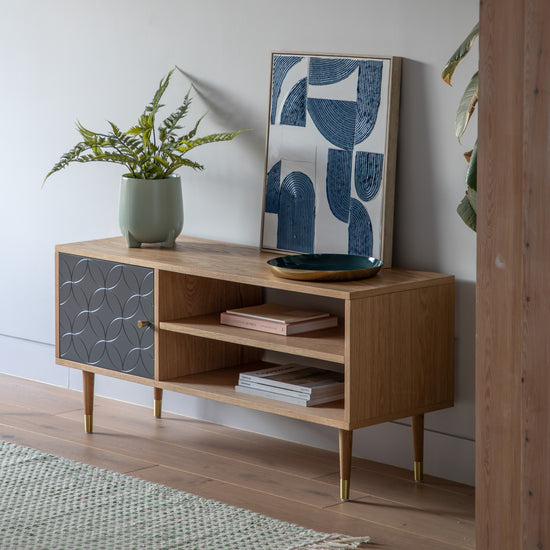 A stylish and functional home furniture piece, the Newbury Media Unit Oak Grey 1200x400x550mm by Kikiathome.co.uk enhances interior decor while displaying a plant on top.