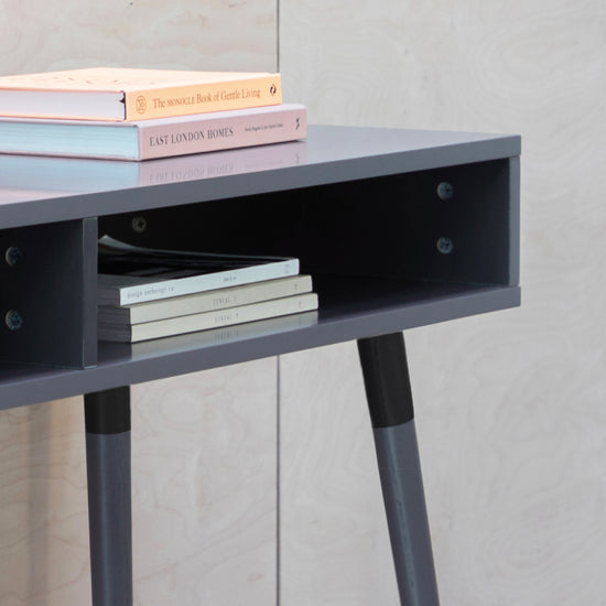 A grey Thurlestone console table, 1100x450x770mm with a book on top, perfect for interior decor and home furniture.