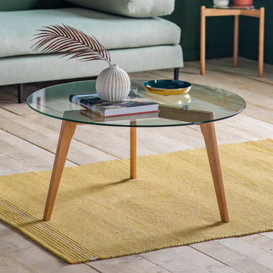 An Ashprington Round Coffee Table Oak 900x900x450mm for home furniture and interior decor on a yellow rug.