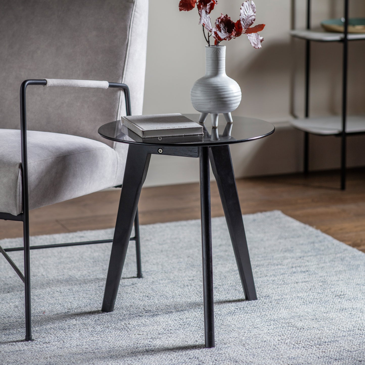 A Black Round Side Table with a vase on top, perfect for interior decor and home furniture.