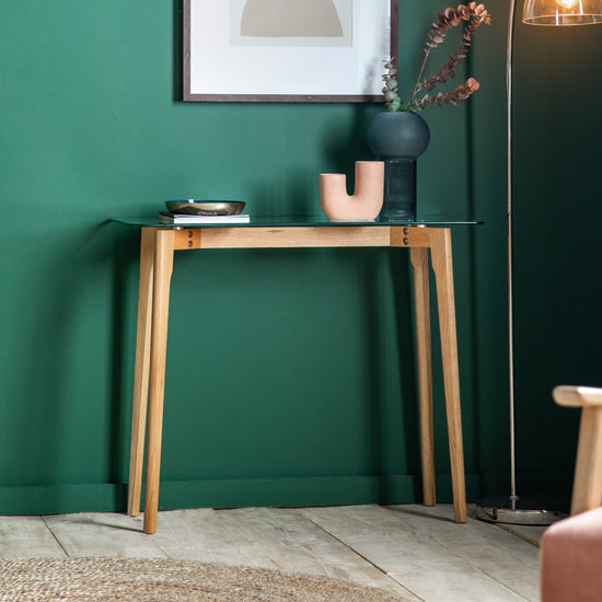 An Ashprington Console Table Oak 900x380x750mm by Kikiathome.co.uk in a living room with green walls, showcasing interior decor.