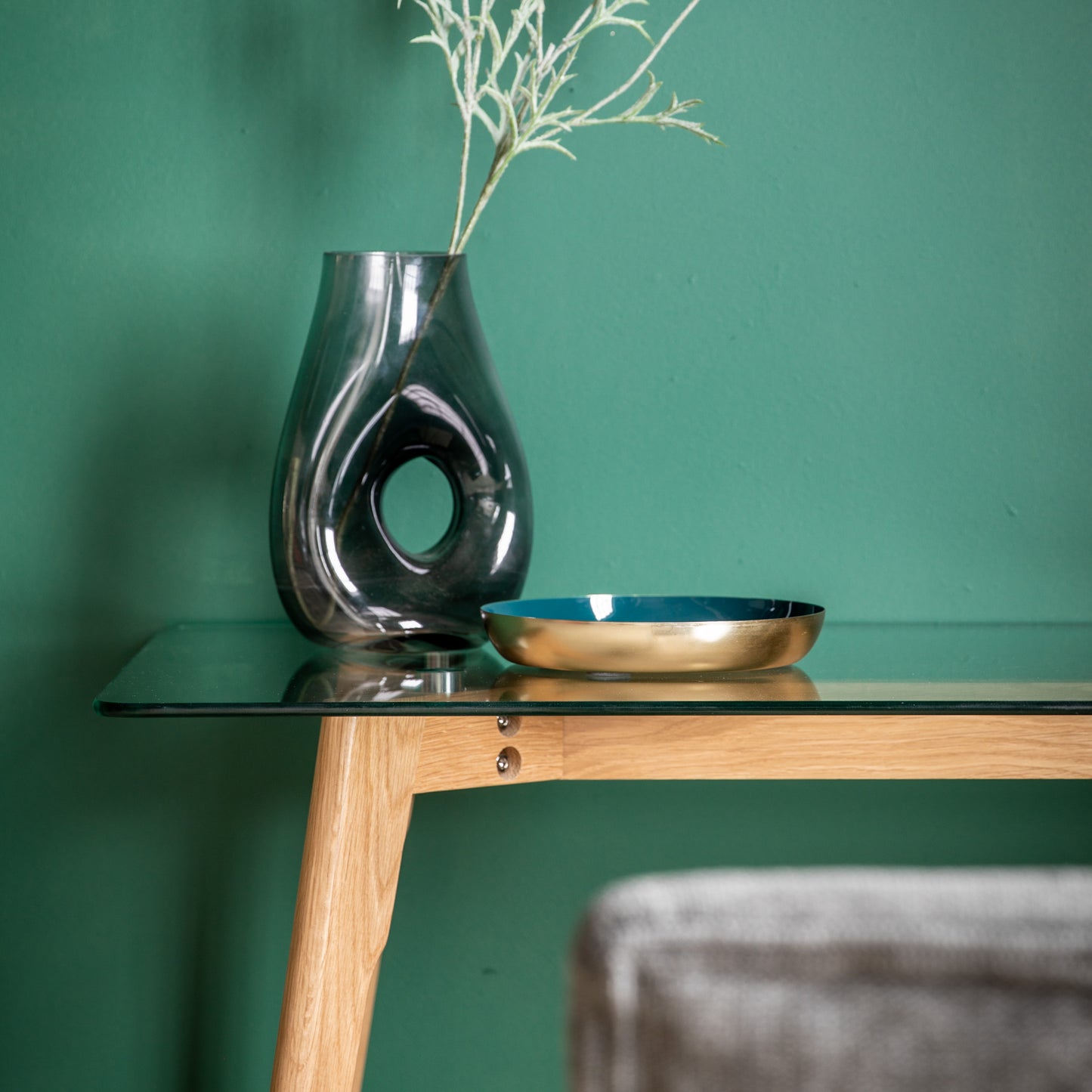 An Oak Desk with a vase on it next to a green wall from Kikiathome.co.uk, perfect for home furniture and interior decor.