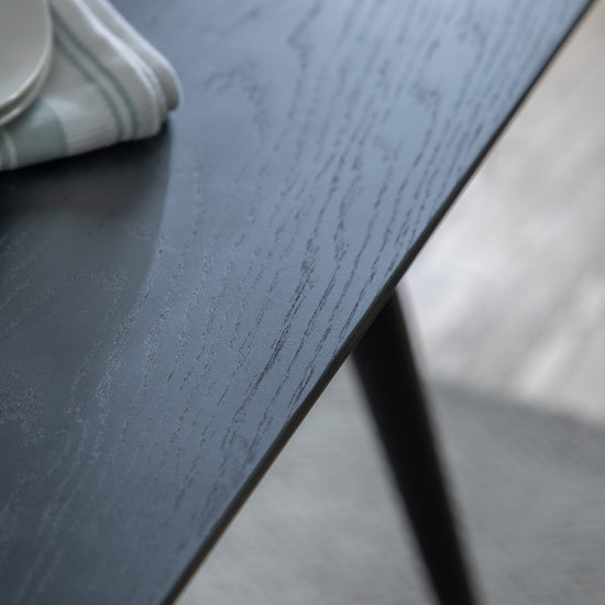 A close up of an Ashford Dining Table Black 1600x900x750mm with a cup on it, showcasing home furniture and interior decor.
