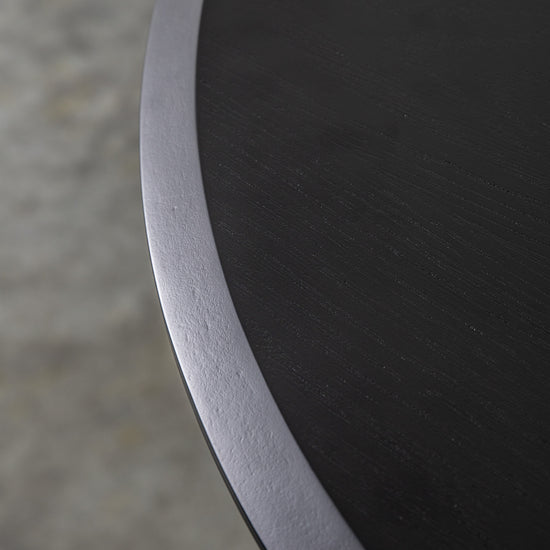 A close up of a Maddox Round Dining Table with a metal base, suitable for interior decor and home furniture.