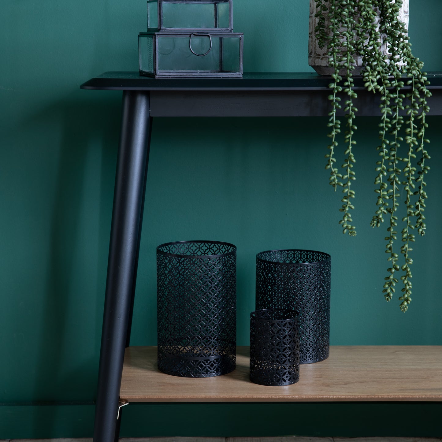 A black Maddox Console Table with Shelf from Kikiathome.co.uk adorned with two vases and a plant, perfect for interior decor.