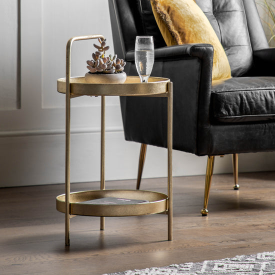 A Sennen Side Table Gold 400x400x720mm for home furniture and interior decor, with a black chair.