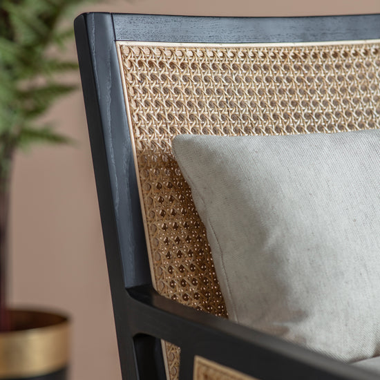 A Nagoya Armchair Cream from Kikiathome.co.uk, an interior decor piece that includes a cushion and a potted plant for added charm.