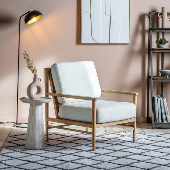 A living room with a cream Oddington armchair from Kikiathome.co.uk and a lamp, showcasing stylish home furniture for interior decor.