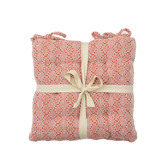 A pink and white cushion with a ribbon tied around it, perfect for interior decor and home furniture.