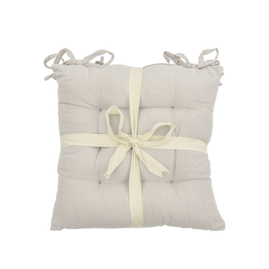 A SC Plain Cotton Seatpad Natural 430x430mm (2pk) seat cushion from Kikiathome.co.uk with an interior decor ribbon tied around it.