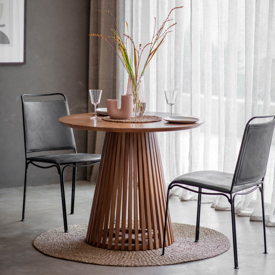 A Ditsum slatted dining table 900x900x760mm with two chairs and a vase, perfect for home furniture and interior decor from Kikiathome.co.uk.