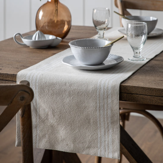 Load image into Gallery viewer, A Stripe Reversible Table Runner in Natural adds interior decor to a wooden table.

