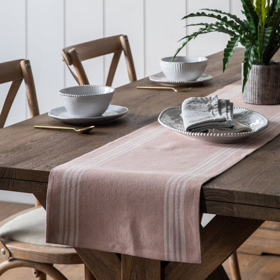 Load image into Gallery viewer, A Blush Stripe Reversible Table Runner 360x2500mm by Kikiathome.co.uk adds a touch of interior decor to a wooden table.
