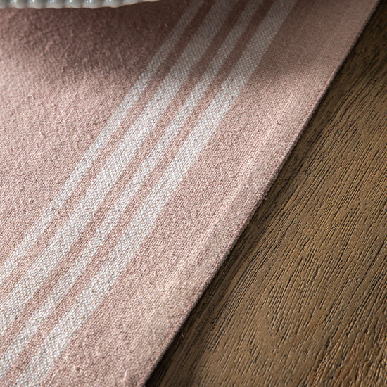 A Blush Stripe Reversible Table Runner from Kikiathome.co.uk adds a touch of interior decor to a wooden table.