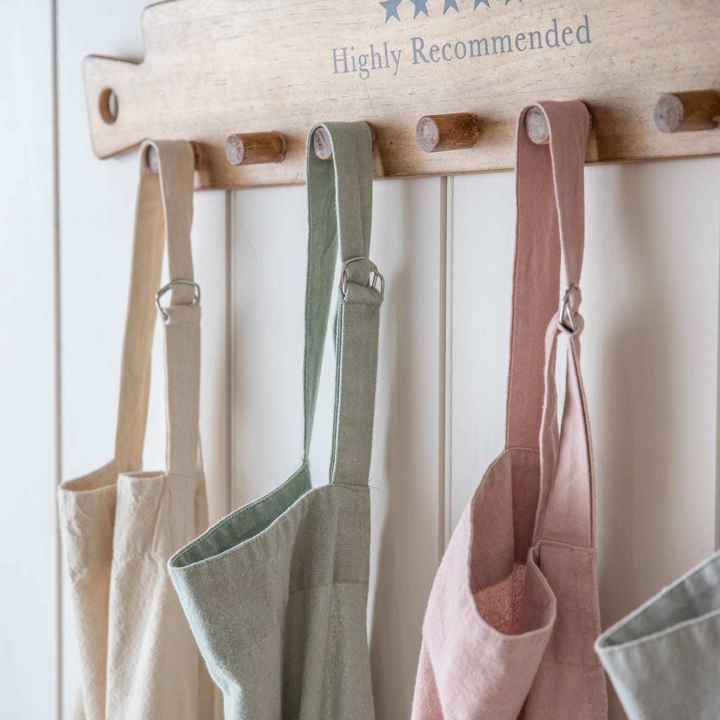 Load image into Gallery viewer, Four Stonewashed Apron Grey 850x900mm hanging on a wooden rack for interior decor.
