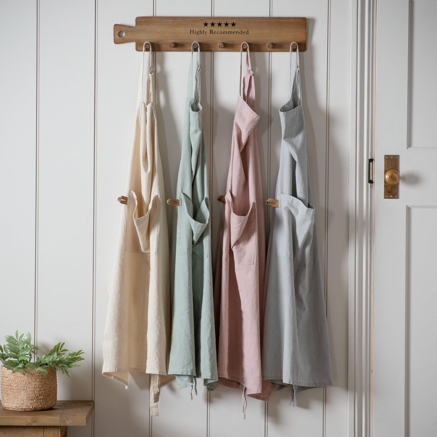 Four Stonewashed Apron Sage hanging on wooden wall from Kikiathome.co.uk, home furniture and interior decor.