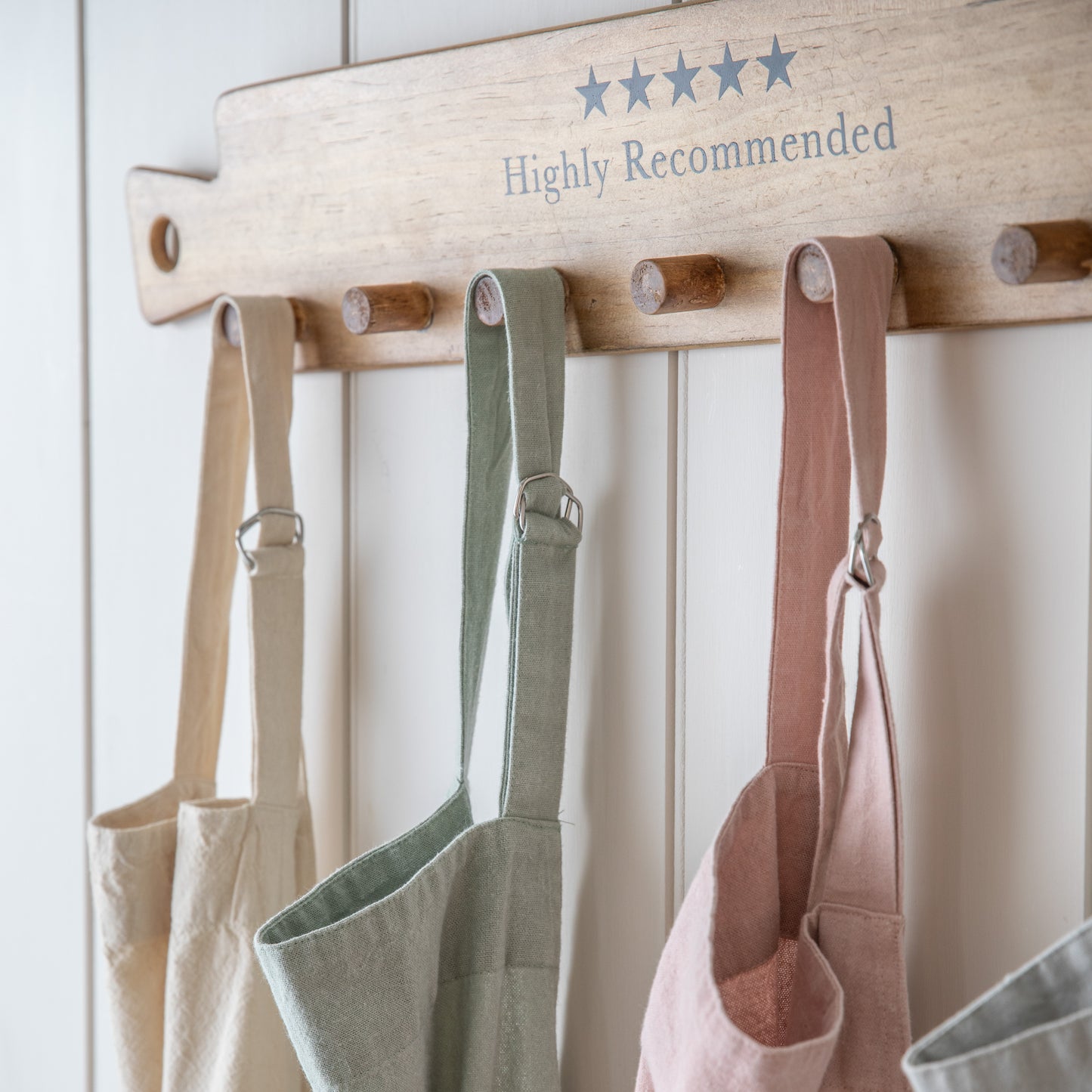 Interior decor: Four Stonewashed Apron Sage 850x900mm hanging on a wooden rack.