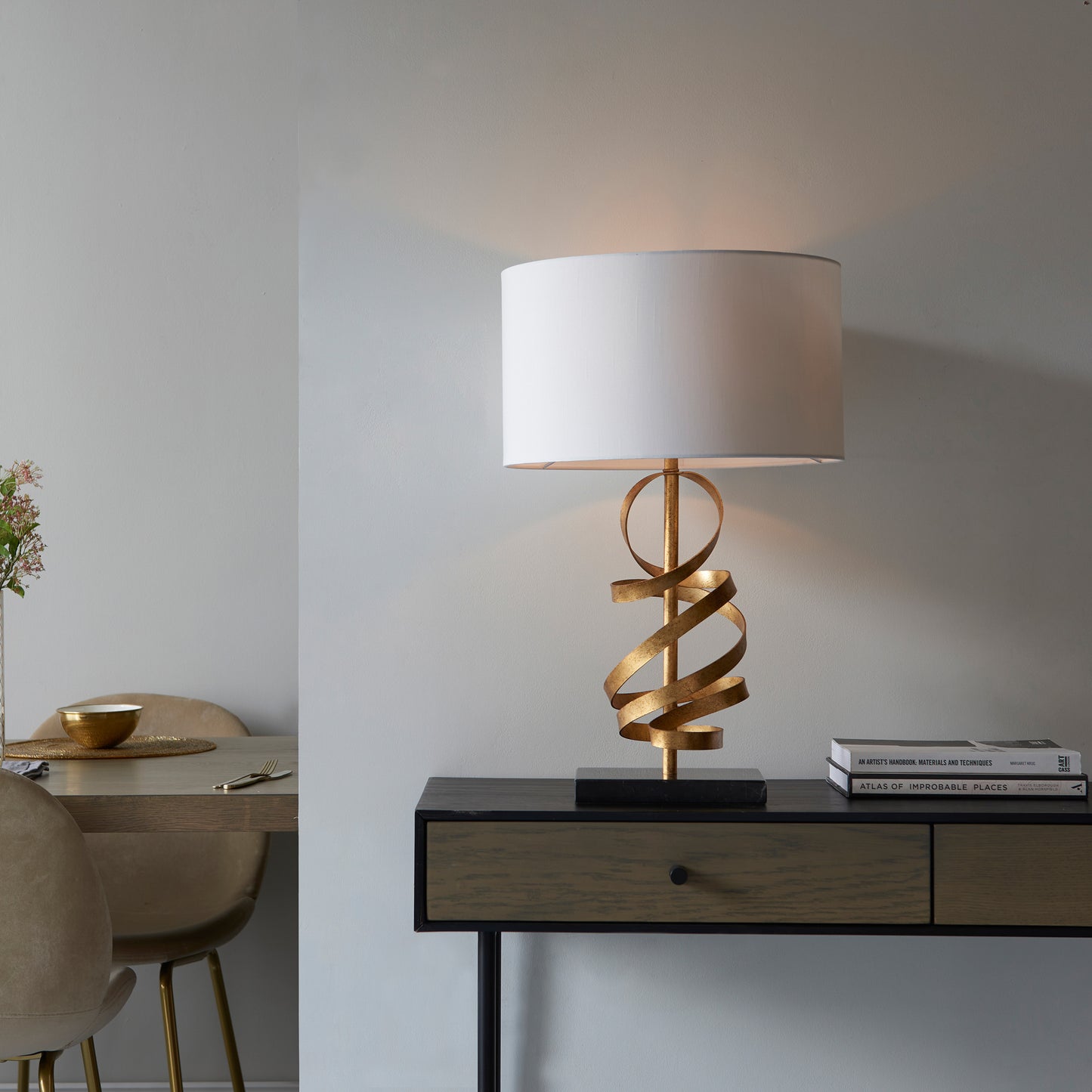 A gold Godfrey table light for home furniture in a room with a table and chairs.