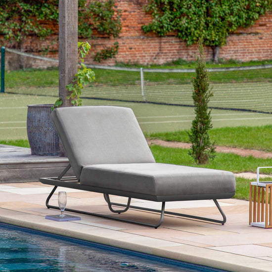 A stylish Topsham Sun Lounger Slate by Kikiathome.co.uk enhances interior decor and provides comfortable home furniture next to a swimming pool.