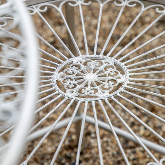 A close up of a Branscombe 2 Seater Bistro Set Vanilla wrought iron table for interior decor.