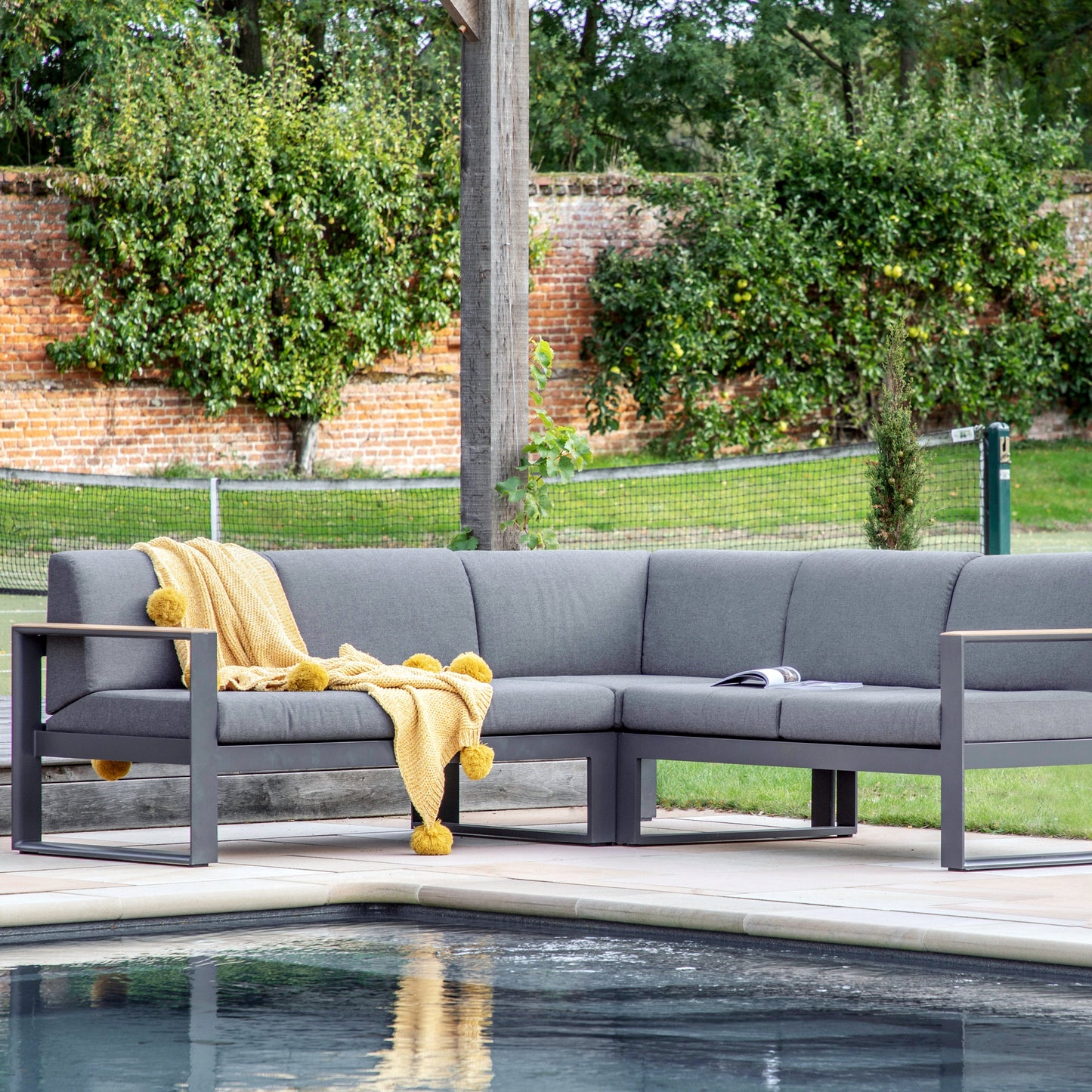 A Cornford Corner Sofa 2180x2180x590mm from Kikiathome.co.uk elegantly placed next to a pool, blending interior decor with outdoor home furniture.