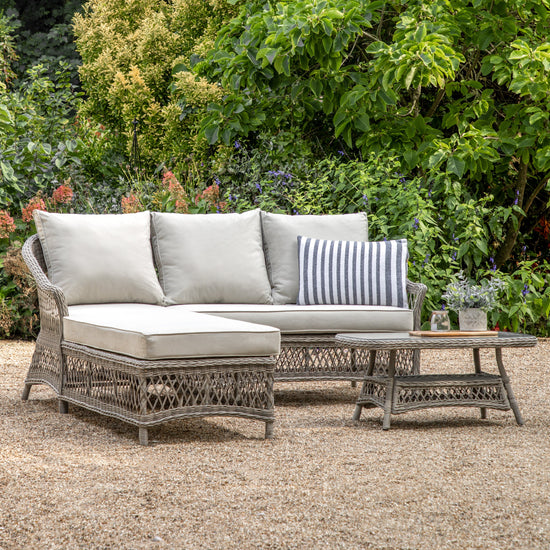 An Allington Chaise Set Stone sofa and coffee table by Kikiathome.co.uk in a garden, adding charm to the exterior with stylish home furniture.