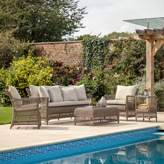 A home furniture set by Kikiathome.co.uk in a garden near a swimming pool.
