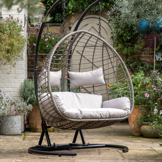 A Woodleigh Hanging 2 Seater Chair for interior decor or home furniture by Kikiathome.co.uk in a garden.