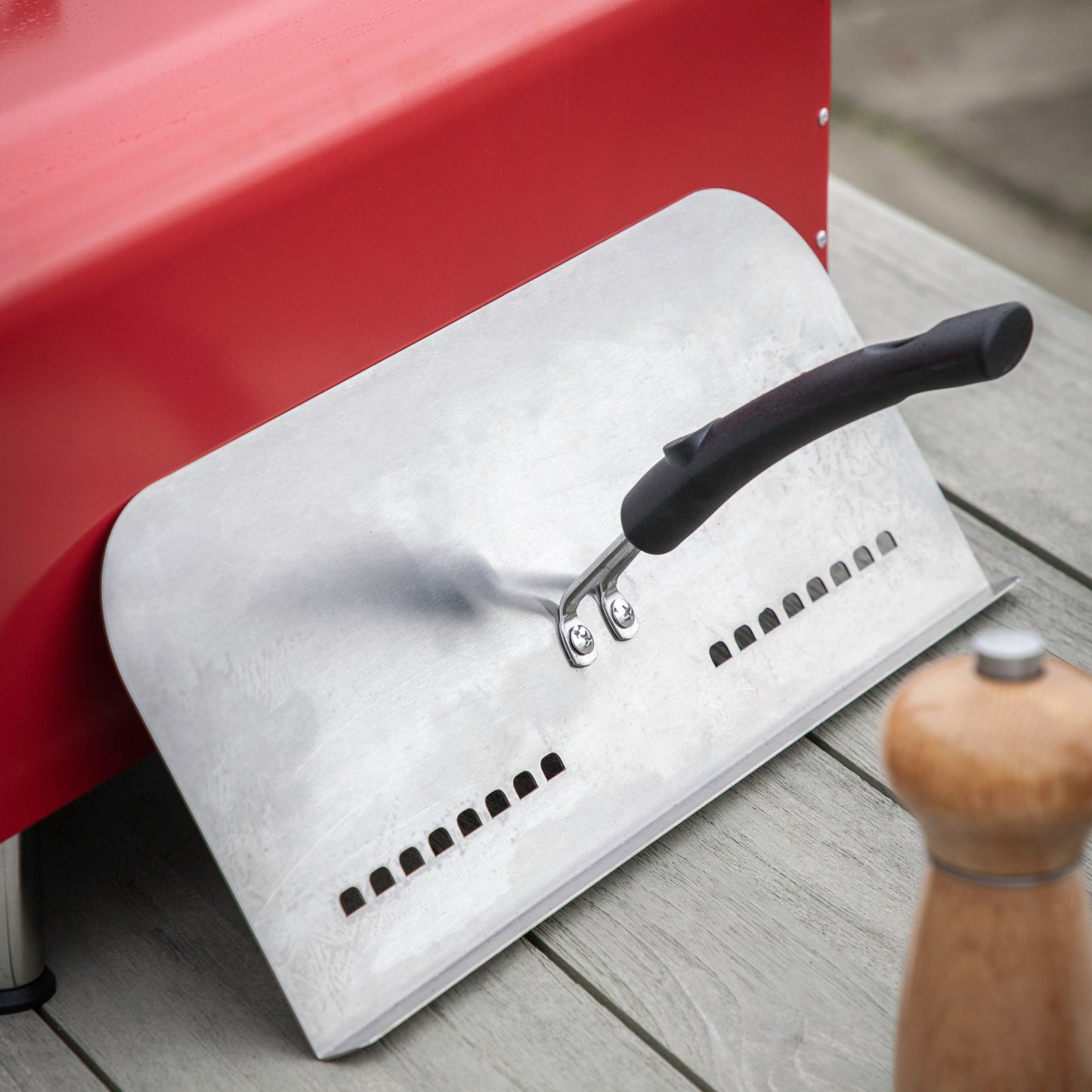A Brixham Pellet Pizza Oven Red with a spatula attached, ideal for home furniture and interior decor.