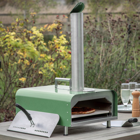 A Brixham Pellet Pizza Oven Green from Kikiathome.co.uk adorning an outdoor table.