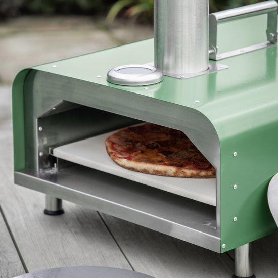 A Brixham Pellet Pizza Oven Green from Kikiathome.co.uk, enhancing the interior decor of a wooden deck at home.