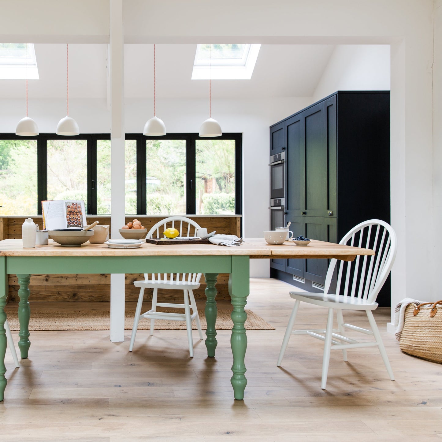 A kitchen with a green table and Farmhouse.co.uk Arch Back Windsor Chairs.