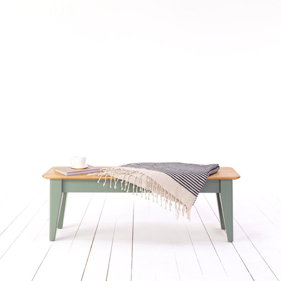 An interior decor item - the Kiki Tapered Leg Bench, adds charm to any living space when adorned with a cozy blanket.