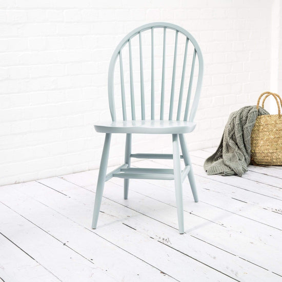 Load image into Gallery viewer, A pair of Arch Back Windsor chairs from Farmhouse.co.uk with a basket next to a white brick wall.
