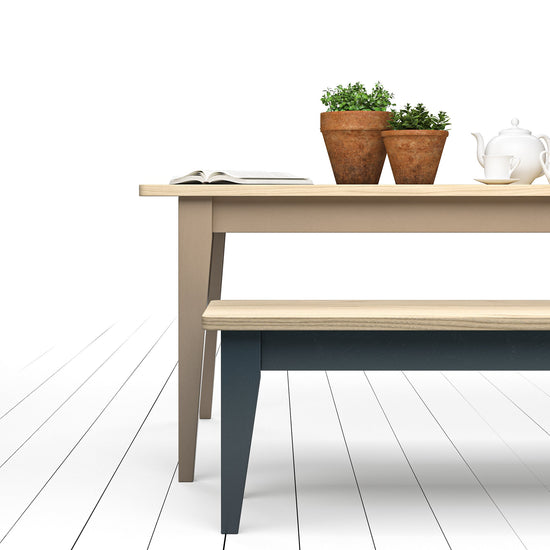 A Kiki Ash Farmhouse Table and bench paired with potted plants for stunning interior decor.