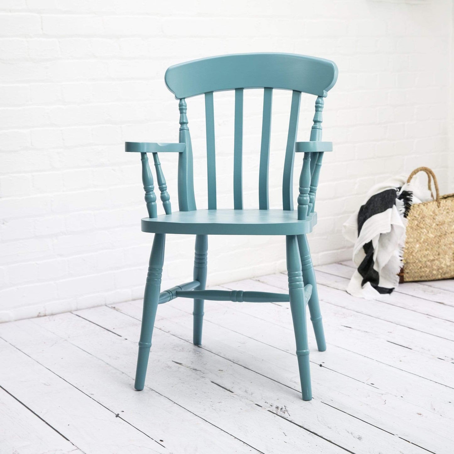 A Kiki Farmhouse Carver Chair adding a touch of interior decor to a white wooden floor in the home.