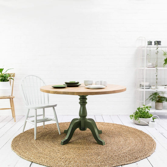 A Prime Oak Round Table by Kiki, a home furniture piece, in a white room with interior decor.